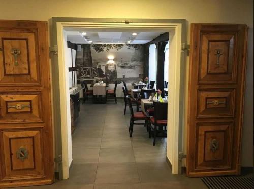 um corredor que leva a uma sala de jantar com mesas e cadeiras em Fachwerk-Hotel Eisenbart em Hannoversch Münden