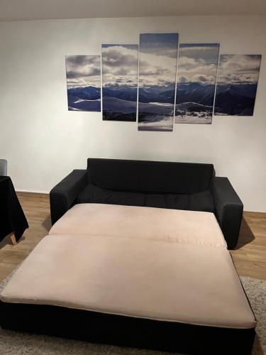 Un sofá negro en una sala de estar con cuatro cuadros. en Ferienwohnung in Oberstdorf mit wundervollem Bergpanorama, en Oberstdorf
