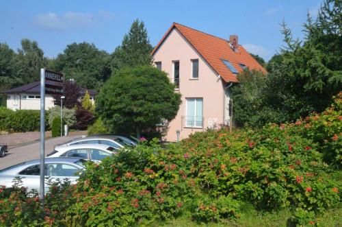 ein rosafarbenes Haus mit Autos auf einem Parkplatz in der Unterkunft Annehill Ferienwohnungen am Wittenborn in Hannoversch Münden