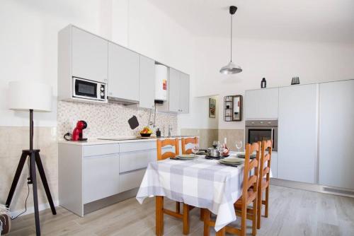 a kitchen with white cabinets and a table with chairs at Altura Beach & Village Escape by Lisbeyond in Altura