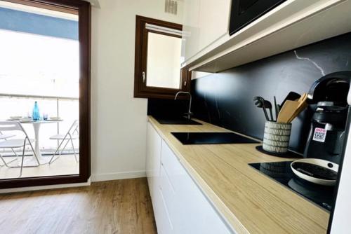 - une cuisine avec un évier et un comptoir avec une fenêtre dans l'établissement Le Temps d'une Pause - 350m de la grande plage, à Les Sables-dʼOlonne