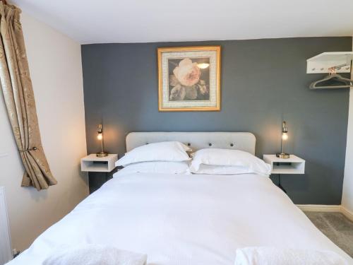 a bedroom with a large white bed with two lamps at Ivy Cottage in Richmond