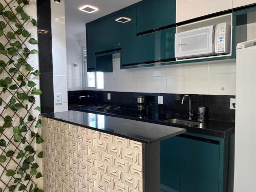 a kitchen with blue cabinets and a black counter top at Praia & Pé na areia Itaparica in Vila Velha