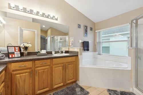 a bathroom with a tub and a sink and a shower at Florida Pool House in Davenport