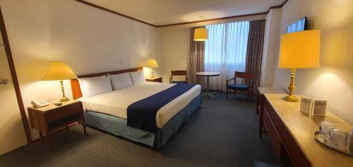 una camera d'albergo con letto, tavolo e sedie di Hotel Bristol a Città del Messico