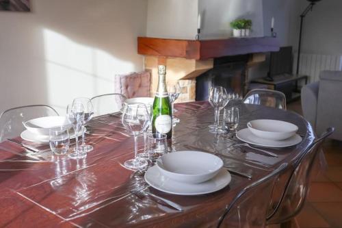 a table with glasses and plates and a bottle of wine at La villa Fontaine in Moussy