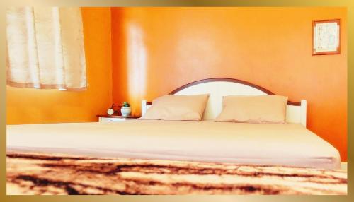 een slaapkamer met een bed met een oranje muur bij Sweetheart Tree Homestay in Bangkok