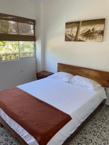 a bedroom with a large bed with white sheets at Hostal Los Arhuacos in Santa Marta