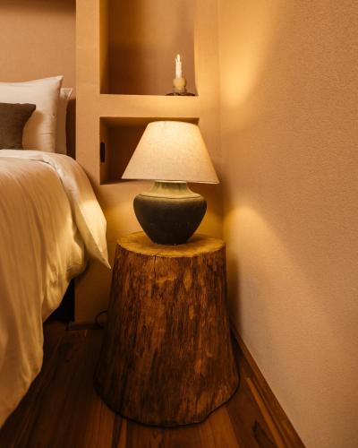 a lamp on a tree stump table next to a bed at Vinha by NHôme in Ponte de Lima