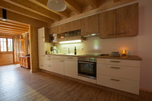 a kitchen with white cabinets and a wooden floor at Arlitscherhof Ferienwohnungen und Chalets in Bad Eisenkappel
