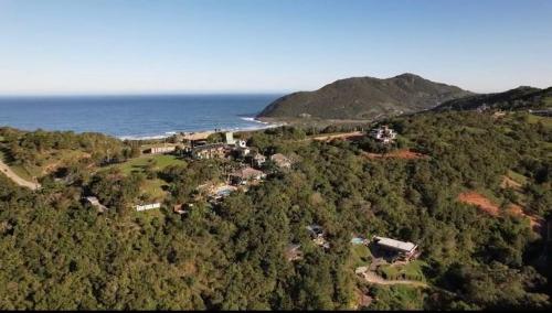 an aerial view of a house on a hill next to the ocean at Silveira Eco Village in Garopaba