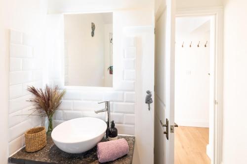 W białej łazience znajduje się umywalka i lustro. w obiekcie Piglets Retreat w mieście Budleigh Salterton
