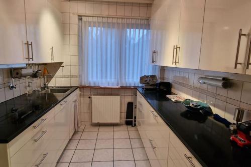 a kitchen with white cabinets and a black counter top at Charmant Appart. dans une Villa in Saint-Louis