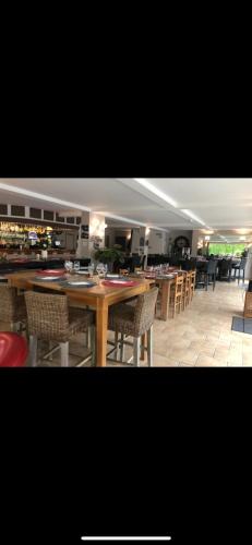 a restaurant with a large wooden table and chairs at Hotel la piscine in Villers-sur-Mer