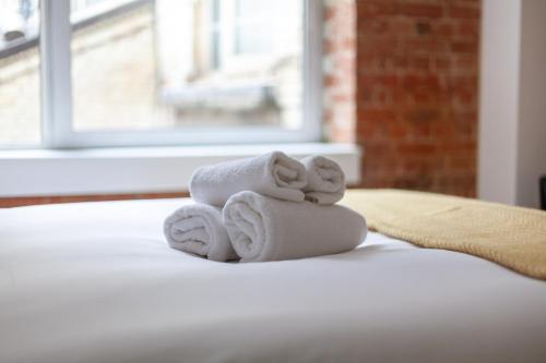 una pila de toallas sentadas encima de una cama en Elegance & Chic Design - 2-bedroom Haven, en Londres