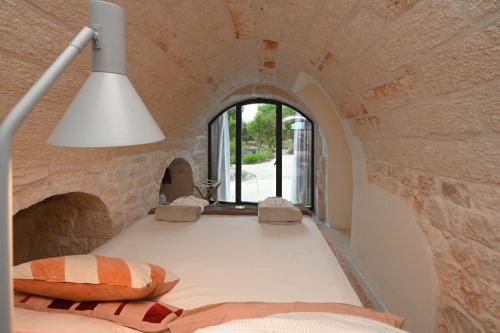 Cette chambre comprend un lit dans un mur en pierre. dans l'établissement Villa Olivida con piscina a sfioro, à Ostuni