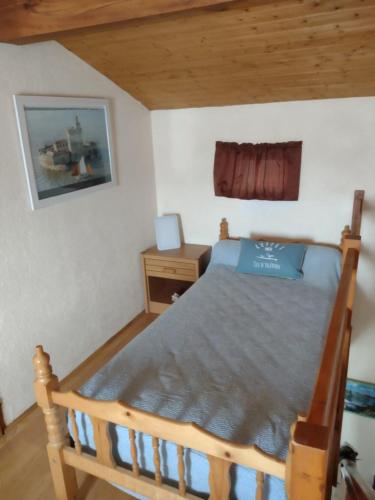 - une chambre avec un lit en bois et un bureau dans l'établissement Séjour tranquille à Oléron, à Grand-Village-Plage