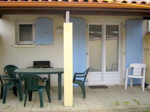 - une table et des chaises sur une terrasse avec une maison dans l'établissement Séjour tranquille à Oléron, à Grand-Village-Plage