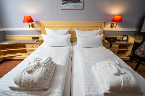 a hotel room with two beds with white towels on them at Hotel Strandperle in Cuxhaven