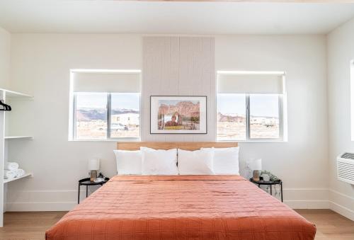 a bedroom with a large orange bed with three windows at Casitas at Capitol Reef in Torrey