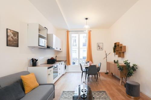 ein Wohnzimmer mit einem Sofa und eine Küche mit einem Tisch in der Unterkunft Charmant appartement proche Opéra Garnier - 4p in Paris