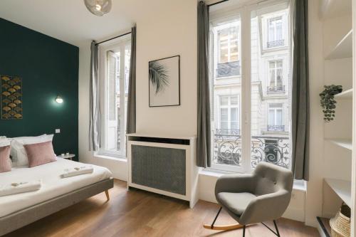 a bedroom with a bed and a chair and windows at Charmant appartement proche Opéra Garnier - 4p in Paris