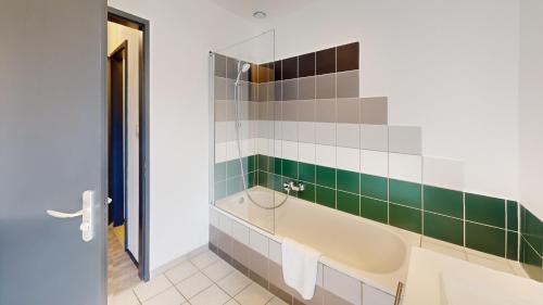La salle de bains est pourvue d'une baignoire et de carrelage vert et blanc. dans l'établissement Bail mobilité Finkwiller, à Strasbourg