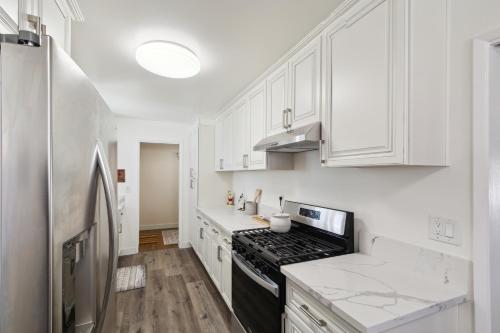 a kitchen with white cabinets and a black stove at Modern Relaxing Retreat with Private Pool home in Azusa