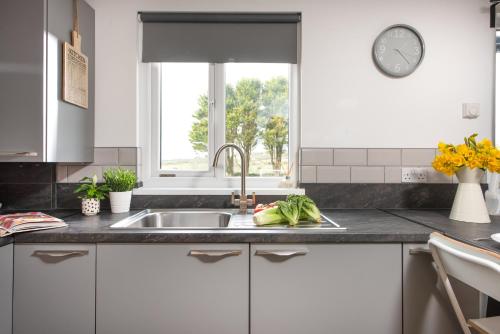 a kitchen with a sink and a window at Wheal Prosper Lodge in Helston