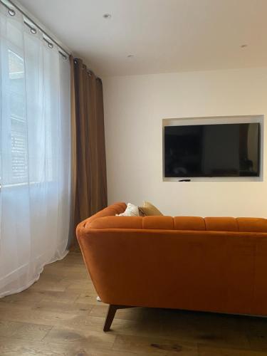 a living room with a couch and a flat screen tv at La Fleur de Sel in Honfleur