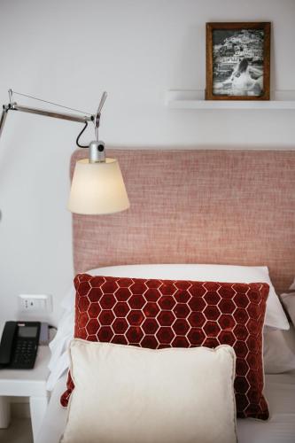 a bedroom with a bed with a red pillow and a lamp at MelRose Relais in Massa Lubrense