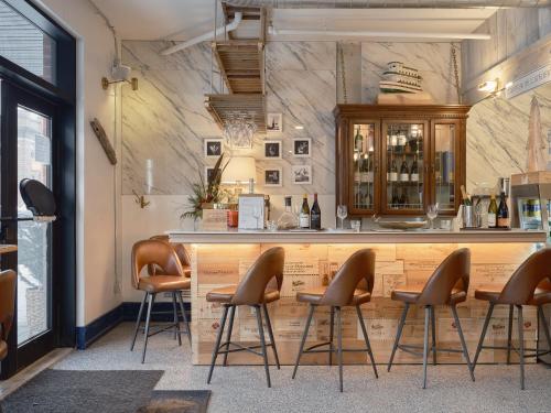 a bar with stools in front of a counter at Hôtel Expérience - Quartier Des Marinas in Magog-Orford