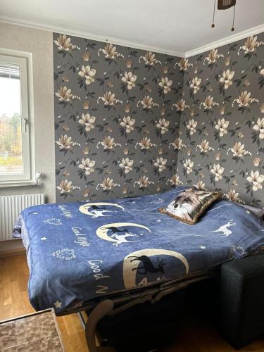 a bedroom with a bed with a blue comforter and floral wallpaper at Sunny ROOM in Stockholm in Stockholm