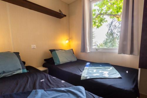 Habitación pequeña con 2 camas y ventana en Camping Bungalows El Far, en Calella