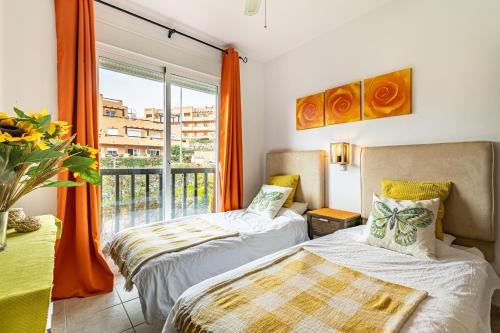 two beds in a room with a large window at Casares del Sol Apartment in Casares