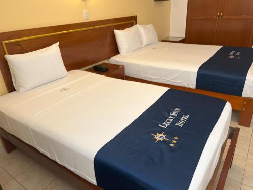 two beds in a hotel room with a blue blanket at Lucky Star Hotel in Chiclayo