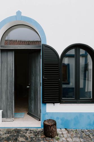 an open door of a house with a tree stump in front at Melides Loft Teatro in Melides