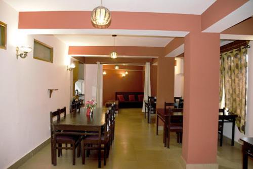 uma sala de jantar com uma mesa e cadeiras e um quarto com um sofá em Pemathang Hotel em Gangtok