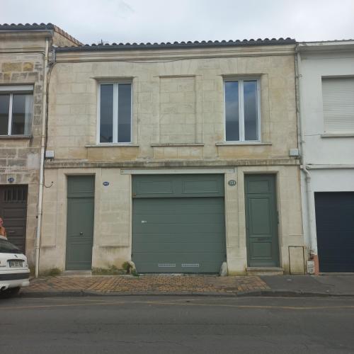 un bâtiment avec quatre portes de garage dans une rue dans l'établissement Bordeaux Chartrons superbe T2 avec terrasse, à Bordeaux
