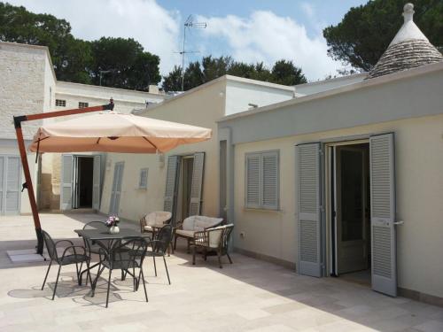 a patio with a table and chairs and an umbrella at Villa Rosato in Selva di Fasano
