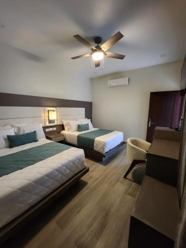 a hotel room with two beds and a ceiling fan at Hotel Tepeu in Santa Elena