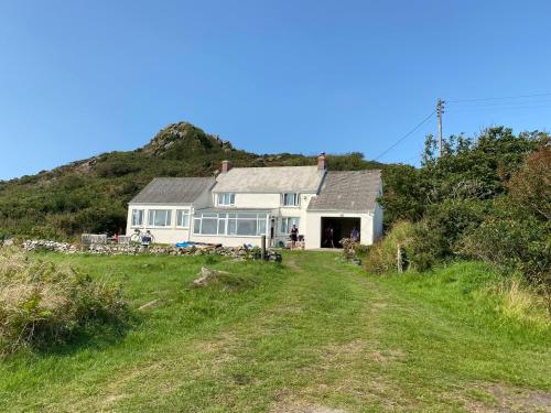 a house on the side of a hill with a dirt road at Pencaer Holiday Cottage in Goodwick