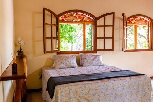 a bedroom with a bed and two windows at Kefi Chalés - Vale do Capão in Palmeiras