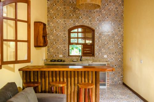 a kitchen with a counter and a bar with stools at Kefi Chalés - Vale do Capão in Palmeiras