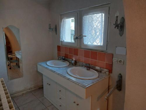 a bathroom with two sinks and a mirror at Chambre Le Serre de Chambon in Labastide-de-Virac