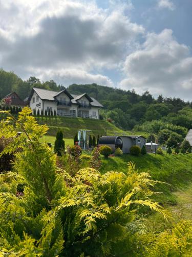 una casa en la cima de una exuberante colina verde en Amaretto Apartamenty-Solina z sauną i ruską banią en Solina