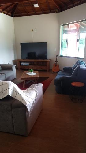 ein Wohnzimmer mit 2 Sofas und einem Flachbild-TV in der Unterkunft Casa Nas Montanhas em Camanducaia Sul de Minas in Camanducaia