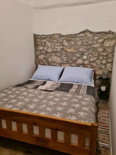 a bedroom with a bed with a stone wall at VILLA KUNTA in Donja Jagodnja