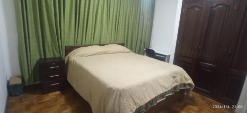 拉巴斯的住宿－Para pareja o familia de 3 integrantes，一间卧室配有一张带绿帘的床