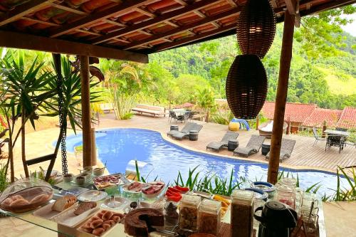 una mesa con comida junto a una piscina en Pousada Sonho Real en Angra dos Reis